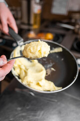 A close-up of mashed potatoes being scooped from a pan with a spoon. The creamy texture showcases a delicious homemade side dish in a kitchen setting.