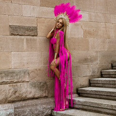 Sexy female model with long legs in sexy pink macrame dress sensually walks around the city.