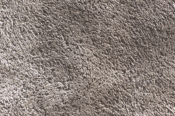 Rough textured concrete wall with natural grooves and shadows, close-up detail.