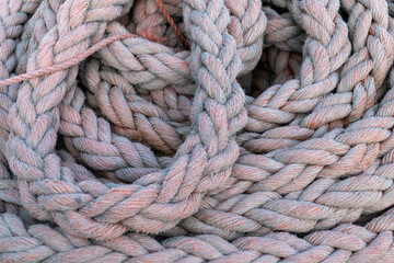 A robust, tightly braided, weathered rope coiled neatly aboard a vessel.