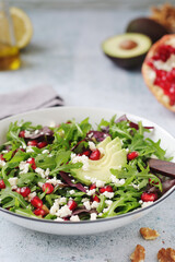 A plate with green rocket salad with pomegranate and avocado
