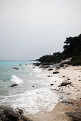 A coastal landscape showcasing gentle waves crashing against a rocky shoreline