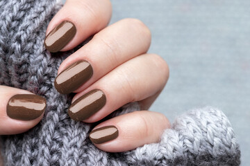 Female hand with beautiful trendy manicure - brown, mocha mousse glittered nails. Demonstrating...
