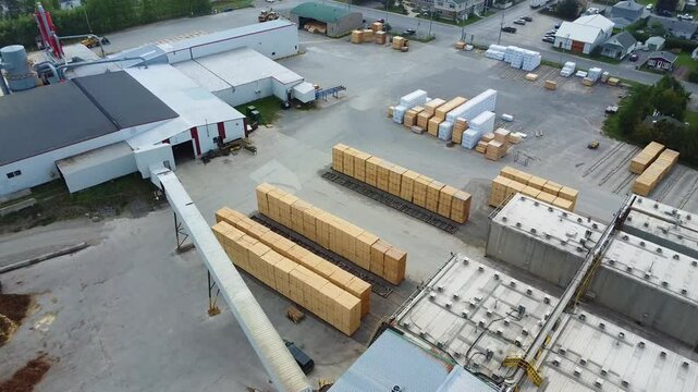 Aerial video capturing industrial sawmill facilities dedicated to drying and processing construction wood, featuring neatly aligned lumber piles ready for export in Price, Quebec, Canada.
