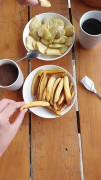 Pov of sharing pinoy merienda food of fried banana and sweet potatoe or kamote served with black coffee and sikwate or hot chocolate drink, authentic local cuisine and culture of the Philippines