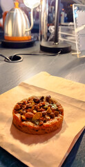 Cookie with various kinds of nuts, almond, cashew, hazel, peanut, on paper bag in bakery shop with kettle in background