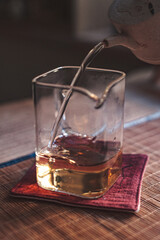 An Elegant and Refined Pour of Rich Whiskey into a Glass, Resting on a Colorful Coaster