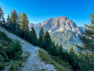 Hiking trail towards mountain peak Jof di Miezegnot with scenic view of rugged massif Jof di...