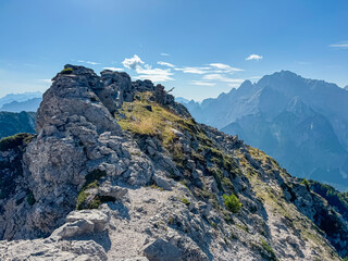 Hiking trail along remains of defensive line first world war on top of Jof di Miezegnot. Surrounded by majestic ridges of Julian Alps shrouded in misty haze, Friuli Venezia Giulia, Italy. Wanderlust