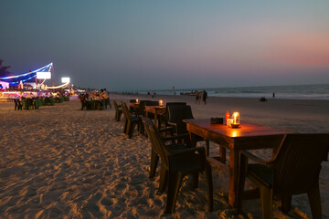 Night view of Beach restaurant shacks and sun beds in north Goa India. Party at sunset in GOA India. Tropical sunny beach party at Sunset with Sun umbrellas loung