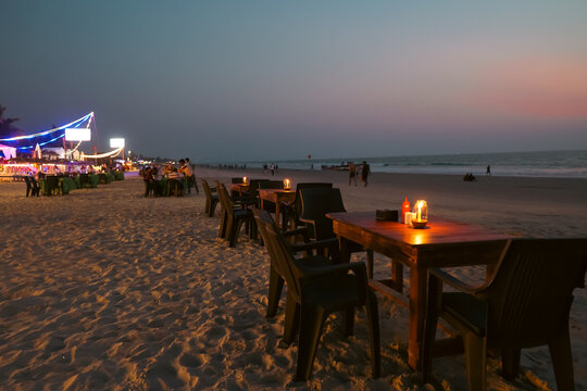 Night view of Beach restaurant shacks and sun beds in north Goa India. Party at sunset in GOA India. Tropical sunny beach party at Sunset with Sun umbrellas loung