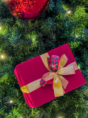 Elegant Red Christmas Gift with Golden Ribbon on Festive Tree
