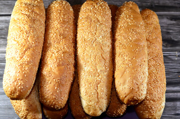 Pile of long sesame buns bread, a fresh baked loaf of bread French Fino ready to fillings, usually filled with savory fillings, made from a dough of flour, milk, yeast and butter