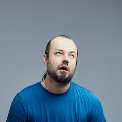 Frustrated man rolling his eyes on a grey background