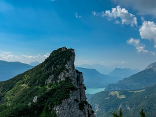 Majestic rugged sharp rock formation overlooking alpine lake Lago di Molveno in valley Andalo Paganella, Trentino, Italy. Surrounded by pristine wild mountain range of Brenta Dolomites, Italian Alps