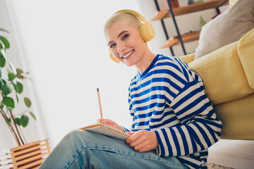 Young woman with blond hair enjoying a relaxed weekend at home, wearing casual striped pullover and...