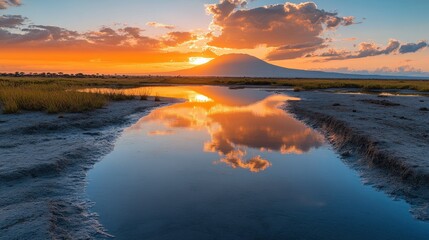 Sunset reflecting on calm water with mountain in background.
