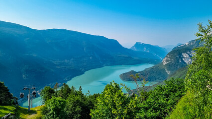 Obraz premium Cable car Funivie Molveno Pradel overlooking alpine lake Lago di Molveno in mountain retreat town Molveno, Trentino, Italy. Surrounded by forest and mountains of Brenta Dolomites. Tourism in Alps