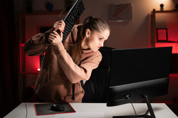 Angry computer gamer-streamer woman breaks keyboard after being defeated in online video game at...