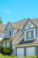 Top of grey stucco luxury house with shingle roof, red and yellow trees and nice windows in Summer in Vancouver, Canada, North America. Day time on June 2024.