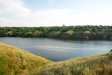 Fototapeta premium Scenic river view with lush green hills and a serene water body under a clear sky, perfect for nature and landscape photography enthusiasts