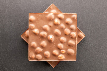 Dark chocolate with hazelnuts on slate stone, close-up, top view.