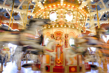 Beautiful carnival fair carousel in motion with animals and yellow lights
