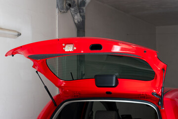 Trunk latch on an open trunk of a red vehicle.