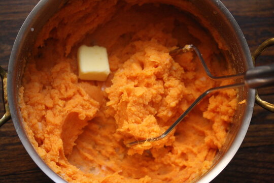 Overhead view of Sweet Potato Mash with a knob of butter in a saucepan 