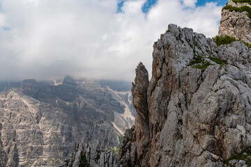 Sharp steep rock formation with view of cloud covered majestic mountain peaks Brenta Dolomites, Trentino, Italy. Wanderlust in alpine wilderness Italian Alps. Hiking in National Park Adamello Brenta