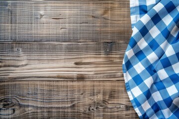 Cloth napkin at empty wooden background top view. Checkered blue tablecloth is on the side of old wood brown table surface. Copy space. Kitchen blank counter. Free space for product and information