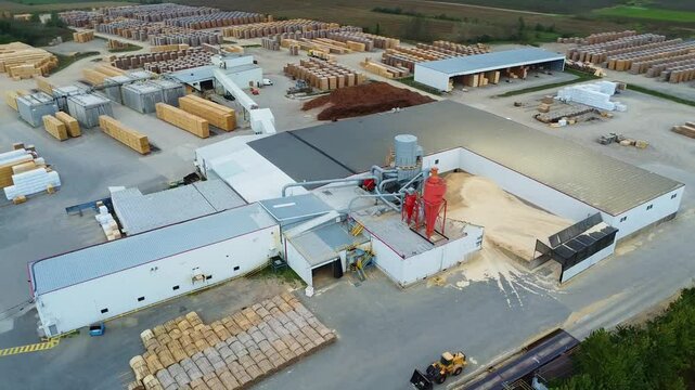Aerial view of a sawmill equipped with a wood dryer, cyclones, a baghouse dust collector and a large wood storage yard.