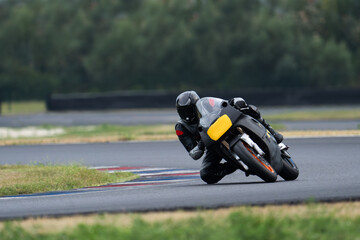 Naklejka premium Motorcycle rider on a black sport bike riding fast through a corner and dragging a knee