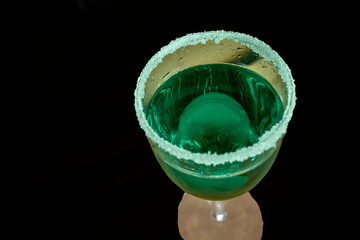 Green liquor cocktail with sugared rim on black background celebrating St. Patrick’s Day