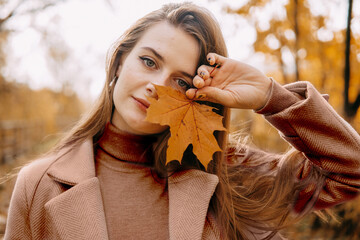 beautiful long-haired woman walks through the autumn streets. Railway, autumn, woman in a coat. Demonstrating the colors of 2025 - Mocha Mousse.