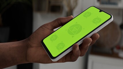 Black African-American middle aged male using smartphone with a blank green screen. Mobile app video mockup. Vertical phone orientation