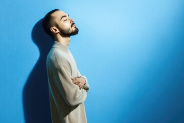 Calm young caucasian male in sweater against blue background with shadow