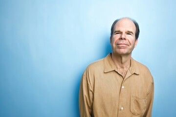 Obraz premium Mature caucasian male in beige shirt against blue background