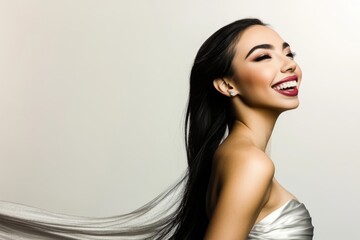 Young asian female in elegant dress smiling against light background