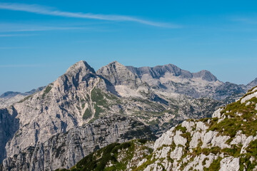 Obraz premium Scenic view of pristine rugged mountain peaks of Kanin massif, Julian Alps, Italy, Europe. Wild hiking trail along majestic ridges in Triglav National Park. Wanderlust alpine wilderness in summer. Awe