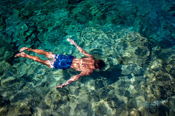 Man swimming underwater in crystal clear turquoise sea