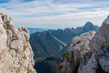 Rock formations framing scenic view of majestic mountain peak Mangart in Julian Alps, Italy Slovenia. On top of Cima Del Lago overlooking Upper Soca valley in Triglav National Park. Alpine wilderness