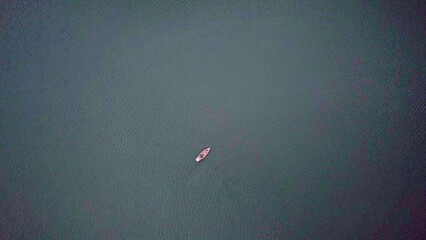 A solitary boat gently glides across the vast calm waters, surrounded by serene beauty. Stock Clip