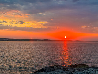 Breathtaking fiery sunset over calm Adriatic Mediterranean Sea in Premantura, Istria peninsula, Croatia, Europe. Reflection of the sun on water creates shimmering path that extends towards horizon