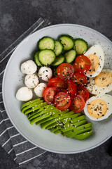 Fresh salad- tomato, avocado, cucumber, mozzarella, egg in a plate. 