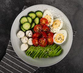 Fresh salad- tomato, avocado, cucumber, mozzarella, egg in a plate. 