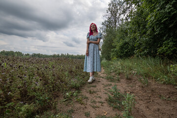 Young beautiful girl with red hair in nature in a beautiful summer dress.