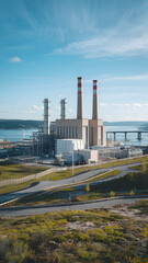 Obraz premium A modern power plant with multiple chimneys and industrial buildings, surrounded by greenery and roads, under a sky.