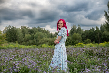 Young beautiful girl with red hair in nature in a beautiful summer dress.