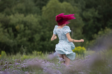 Fototapeta premium Young beautiful girl with red hair in nature in a beautiful summer dress.